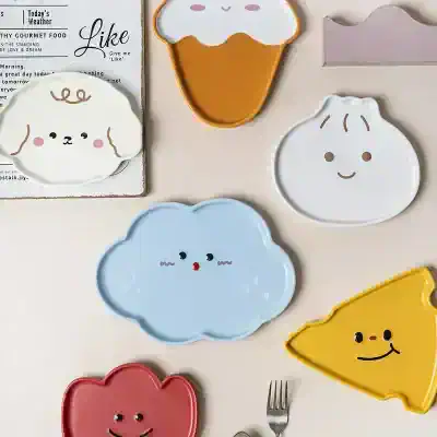 Colorful cute cloud and food-shaped plates with smiling faces, perfect for children's meals or playful table settings.