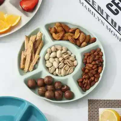 Assorted roasted nuts and dried fruits on a divided serving dish at Monalisa Store for healthy snacking and dietary supplements.