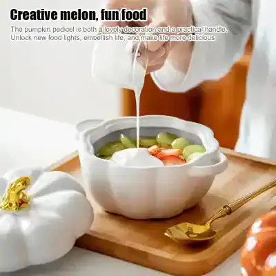 Pumpkin-shaped ceramic bowl with fresh fruit and creamy yogurt, stylishly decorated for serving snacks or desserts.