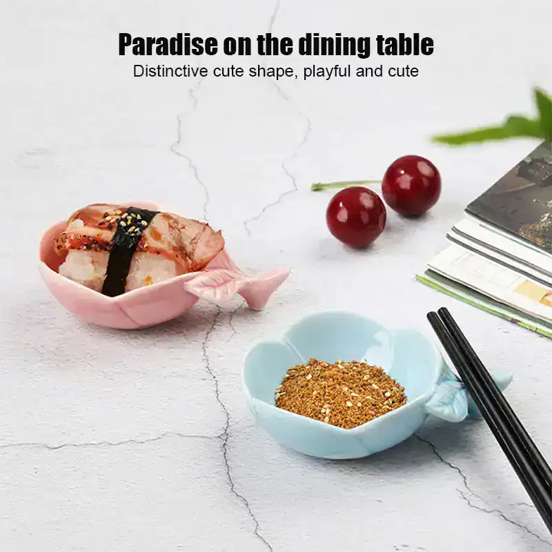 Sushi-shaped bowls on a white textured surface, filled with spice and sauce, with cherries and magazines nearby, emphasizing stylish tableware for dining and kitchen decor.