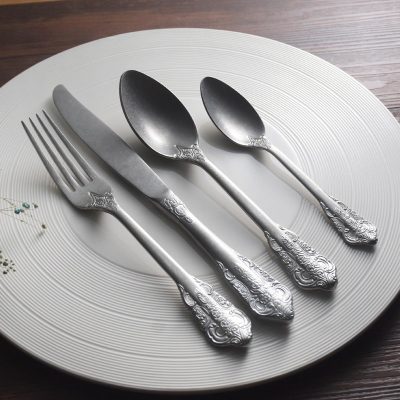 Elegant silver cutlery set including fork, knife, and two spoons on a white decorative plate, perfect for upscale dining and special occasions.