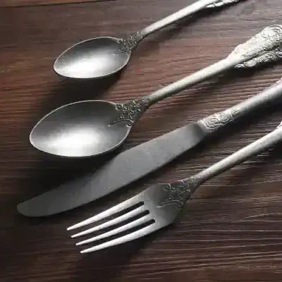 Elegant vintage silverware set including teaspoons, knife, and fork with ornate handles, displayed on wooden surface, perfect for dining and collection purposes.