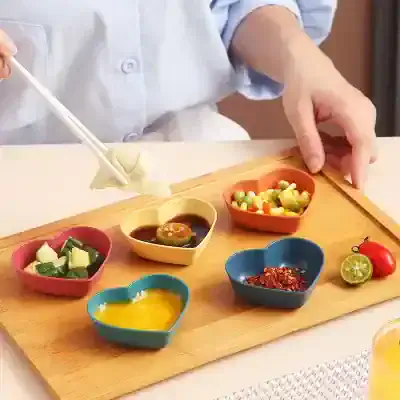 Colorful heart-shaped condiment bowls with Asian sauces and garnishes on wooden tray at Monalisa Store.