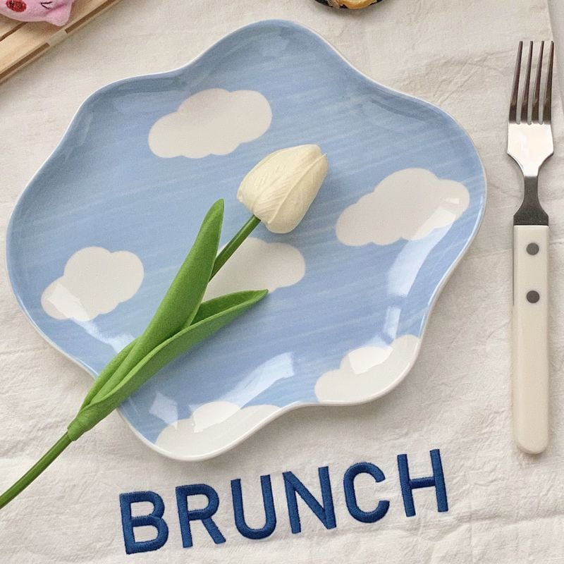 White tulip flower on blue cloud-patterned plate for brunch setting.