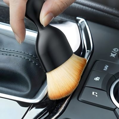 Microfiber cleaning brush on car dashboard for interior detailing and maintenance.