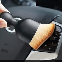 Microfiber cleaning brush used for car interior detailing, shown on a steering wheel, ideal for maintaining cleanliness and hygiene in automotive environments.
