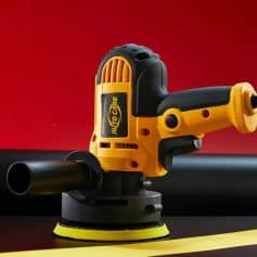 Electric power sander tool on a black surface with a red background.