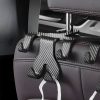 Suction cup hooks attached to a car seat headrest for organizing accessories, featuring a sleek black and carbon fiber design. Perfect for car organization and convenience.