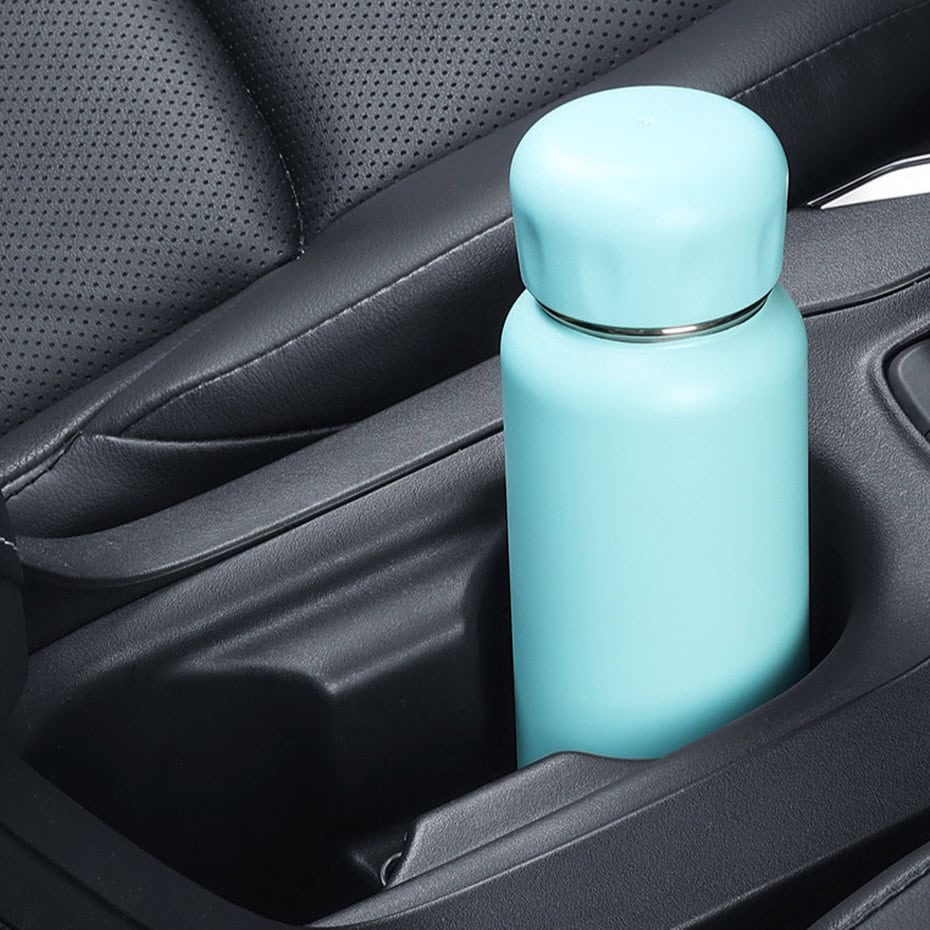 Recyclable turquoise insulated water bottle in car cup holder for eco-friendly hydration solutions.