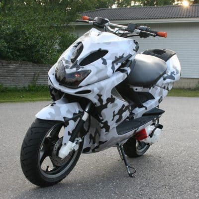 Camouflage motorcycle parked outdoors at dusk, showcasing a sporty design ideal for urban commuting and motorcycle enthusiasts. Perfect for highlighting vehicle customization and stylish motorbike accessories.