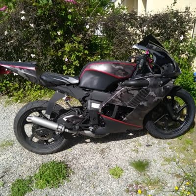 High-performance black and gray camouflage motorcycle with red accents, aerodynamic fairings, and sporty design, perfect for racing or street riding enthusiasts.