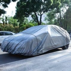 Covering car with protective silver car cover for outdoor protection, dust, and weather-resistant coverage. Suitable for vehicle storage and maintenance.