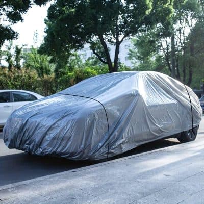 Covering car with protective silver car cover for outdoor protection, dust, and weather-resistant coverage. Suitable for vehicle storage and maintenance.