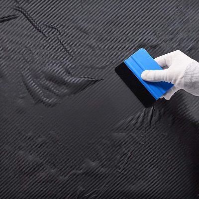 High-quality black carbon fiber sheet with a hand wearing a white glove cleaning or polishing. Perfect for custom automotive, aerospace, or high-performance applications, showcasing durability and modern design.