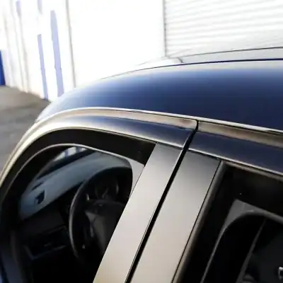 Close-up of a luxury black car's roof and window frame showcasing sleek design and premium automotive aesthetics.
