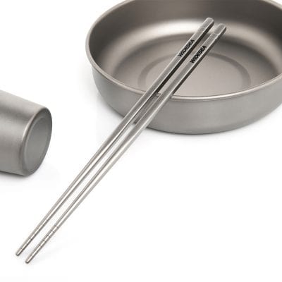 Stainless steel chopsticks and bowls set on a white surface, ideal for modern dining and Asian cuisine, emphasizing quality and durability.
