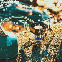 Lightweight portable camping stove with fuel canister outdoor cooking equipment for backpacking and hiking activities.