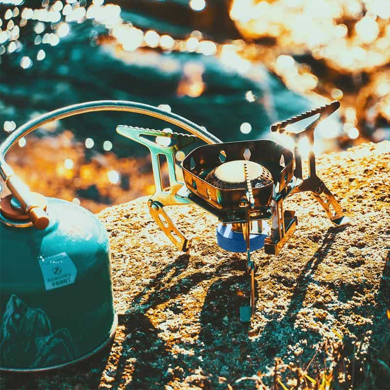 Lightweight portable camping stove with fuel canister outdoor cooking equipment for backpacking and hiking activities.