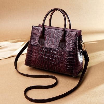 Luxurious deep burgundy crocodile-pattern leather handbag with top handles and adjustable shoulder strap, perfect for stylish women seeking premium fashion accessories.