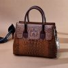Brown crocodile-embossed leather handbag with top handles and luxury detailing for women.