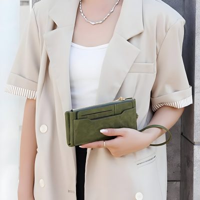 Stylish woman holding a green leather clutch bag, wearing a beige blazer; modern fashion accessories, perfect for professional or casual wear.