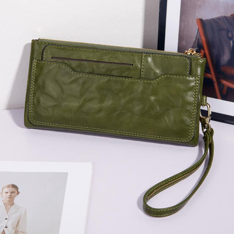 Green leather wristlet purse with a front pocket, zipper closure, and detachable wrist strap, perfect for stylish carrying of essentials.