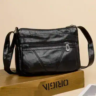 Black leather shoulder bag with multiple zippered compartments, perfect for everyday use or travel, featuring stylish design and durable construction. Ideal accessory for fashion-conscious individuals.