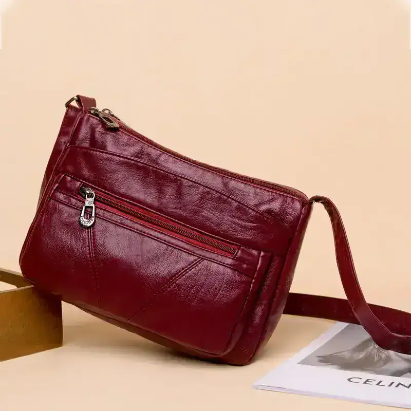 Leather red shoulder bag with zipper compartments for women and men, stylish accessories for daily wear.