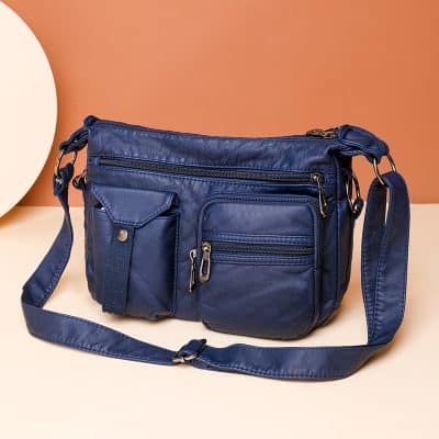 Blue messenger bag with multiple zippered compartments and a front pocket, ideal for optical accessories and eyeglass cases for travel and daily use.