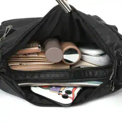 Cosmetic bag with makeup essentials including foundation bottles, brushes, compact powders, and mirrors, ideal for travel and daily beauty routines.
