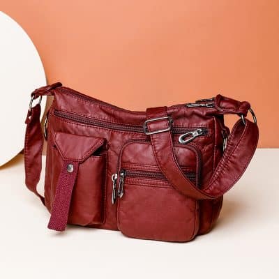 Red leather crossbody bag with multiple zippered compartments and adjustable strap for women.