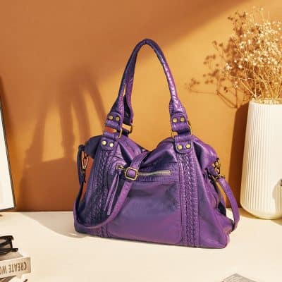 Violet leather handbag with braided details and multiple compartments, stylish accessory at Monalisa Store for fashion-forward individuals.