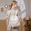 Stylish woman with blonde hair wearing a beige satin jacket and carrying a white leather backpack at Monalisa Store, a popular destination for premium eyewear and optical accessories.
