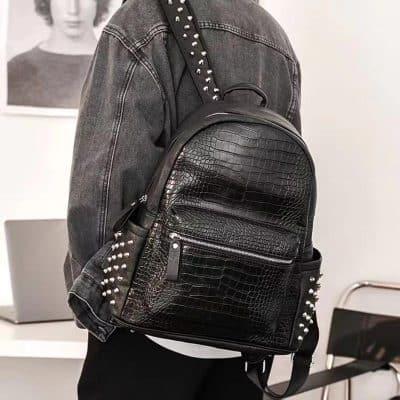 Black faux crocodile leather backpack with silver studded accents for stylish everyday use.