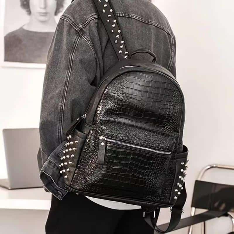 Black faux crocodile leather backpack with silver studded accents for stylish everyday use.