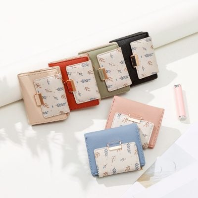 Colorful women’s wallets with floral patterned cardholders on top of pastel notebooks.