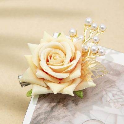 Elegant artificial peach-colored rose hair accessory with pearl accents, perfect for bridal or special occasions. Crafted with detailed fabric petals and decorative pearls for a stylish look.