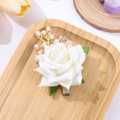 Elegant white floral hair clip with pearl accents, perfect for bridal or special occasions, displayed on a wooden tray.