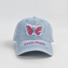 Pink butterfly embroidery on distressed denim baseball cap, "Free Flight" slogan, casual stylish accessory for spring and summer, perfect for outdoor activities and sunglasses.