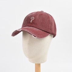 Worn red distressed baseball cap with torn brim displayed on a mannequin head for casual fashion.