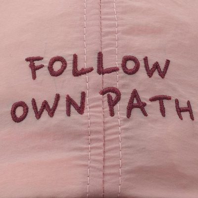 Follow own path embroidered on pink fabric, inspiring individuality and confidence.