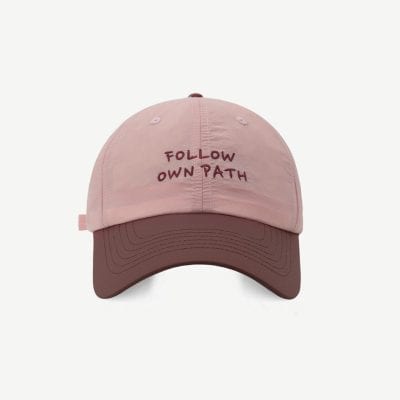 Follow own path embroidered baseball cap in soft pink and brown, adjustable strap, stylish accessory for casual or athletic wear, featuring motivational quote design.