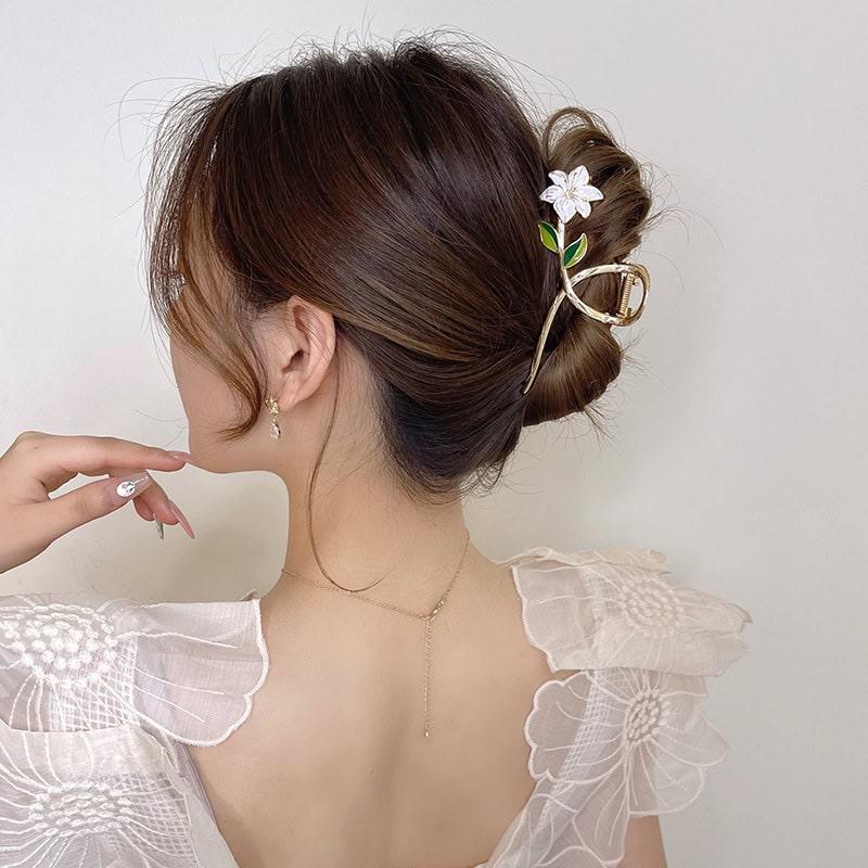Elegant woman with styled updo featuring floral hair accessory, wearing delicate jewelry, showcasing beauty and fashion accessories.
