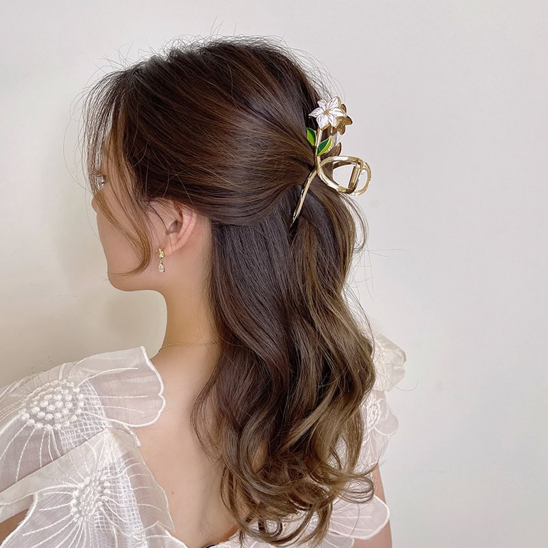 Elegant woman with wavy brown hair styled with floral hair clip and glasses, showcasing fashionable hair accessories and sophisticated look for opt shop customers.