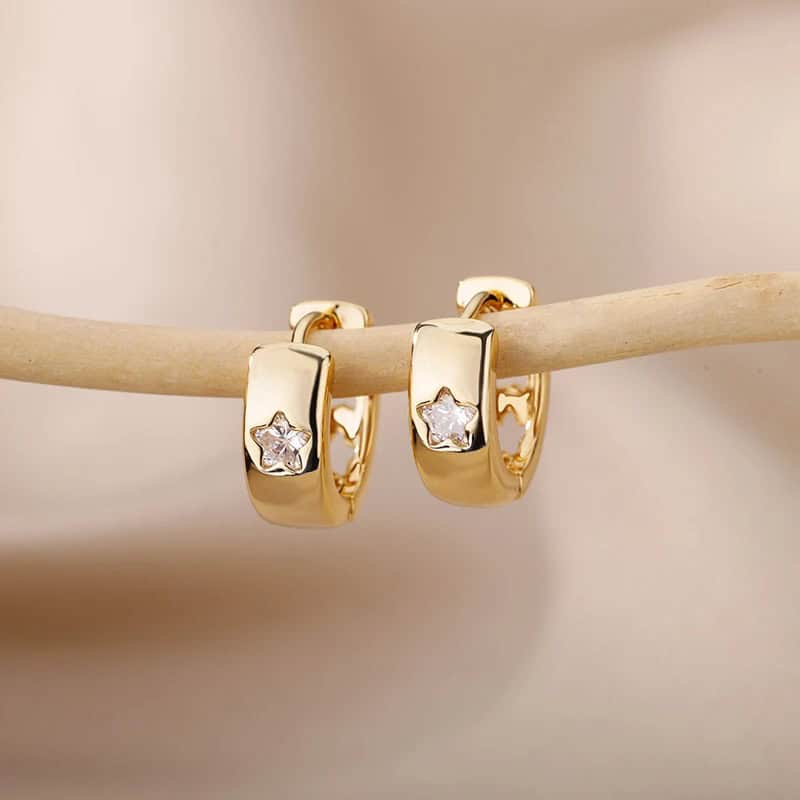 Shiny gold hoop earrings with star-shaped diamond accents displayed on a beige jewelry stick. Perfect for elegant jewelry collections and stylish accessories.