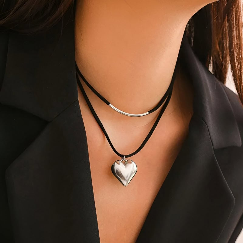 Heart-shaped silver pendant necklace with black cords, stylish jewelry featuring modern design.