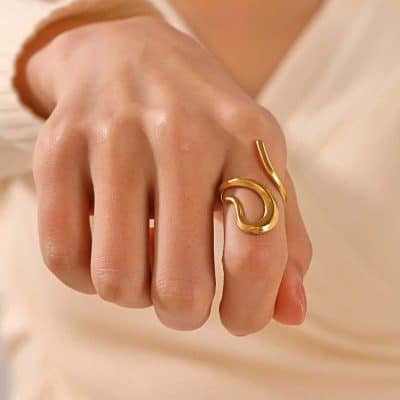 Elegant gold ring with a modern abstract design, worn on a woman's finger, showcasing stylish jewelry suitable for fashion and accessories collections.