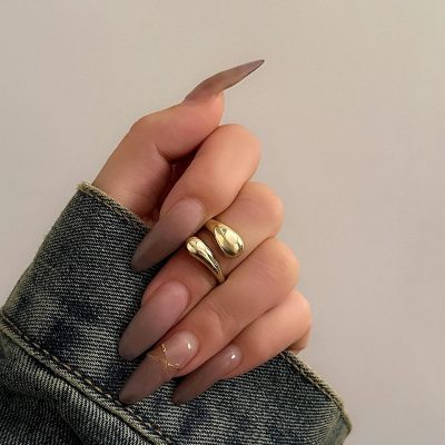 Shiny gold rings on a person's finger, showcasing stylish jewelry for a modern look. The hand is wearing a textured denim jacket, emphasizing elegant accessory options at Monalisa Store.