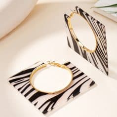 Golden hoop earrings with black and white striped geometric design, displayed on matching black and white patterned stands, ideal for stylish accessories at Monalisa Store.
