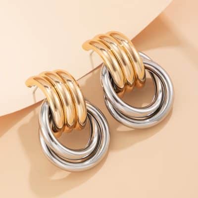 Luxurious gold and silver hoop earrings showcased on a minimalist beige background, perfect for stylish accessories and fashion jewelry enthusiasts.